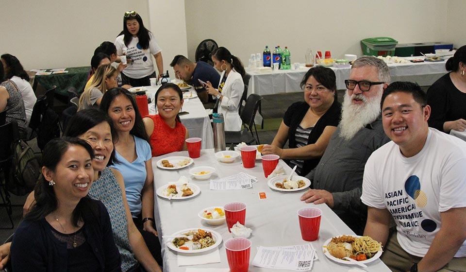 Members of Asian Pacific American Systemwide Alliance sit at a table while meeting.